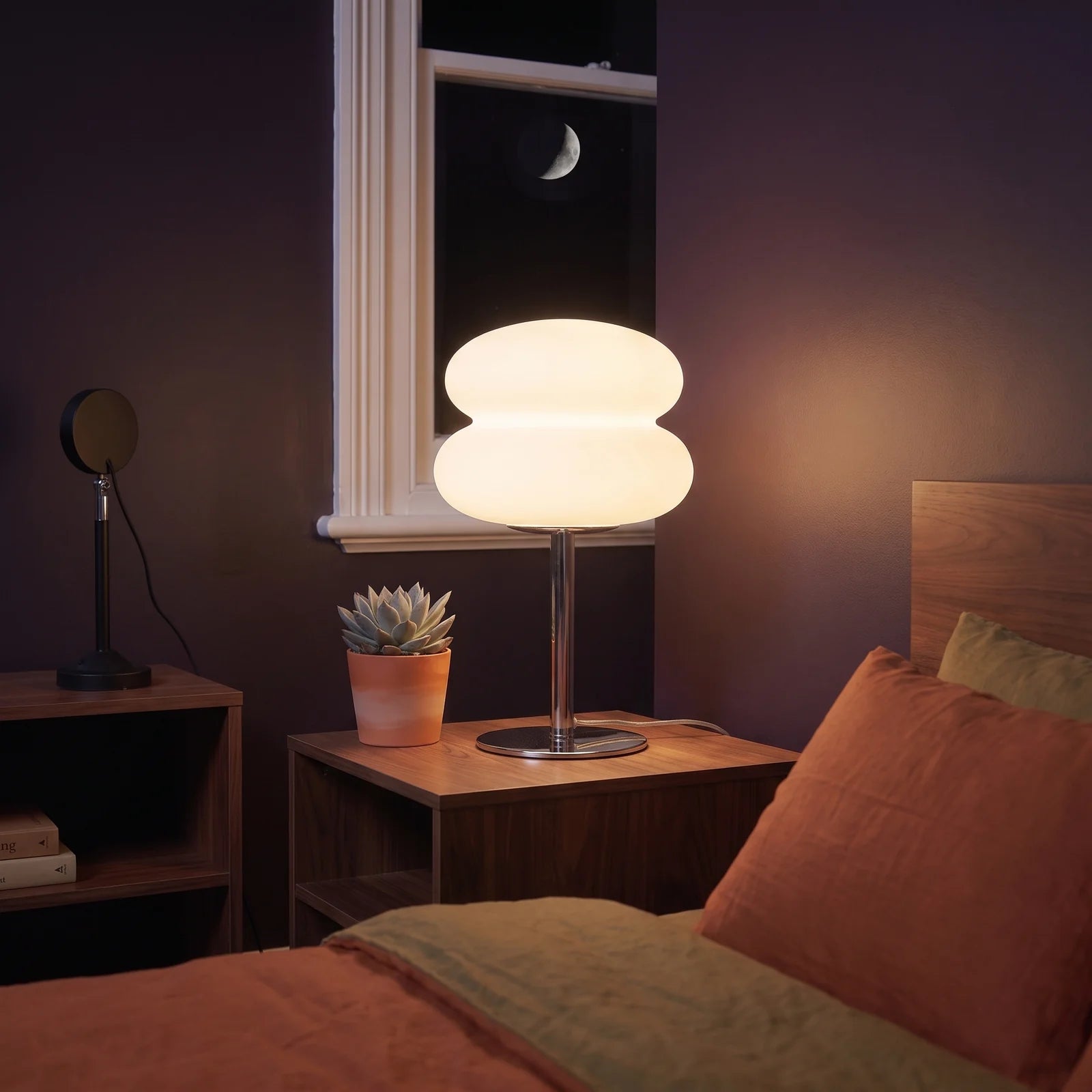 The mushroom lamp glowing on a walnut nightstand