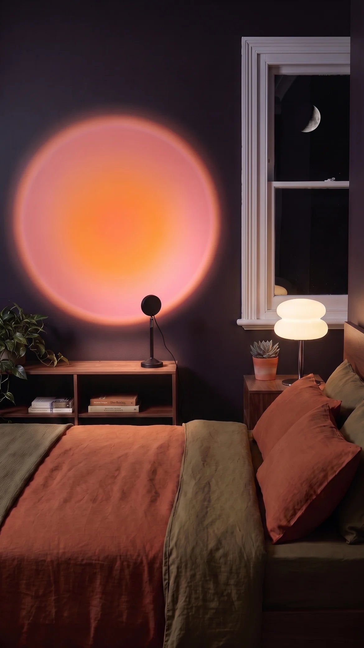 Both lamps on: warm light on the nightstand and a sunset glow on the wall