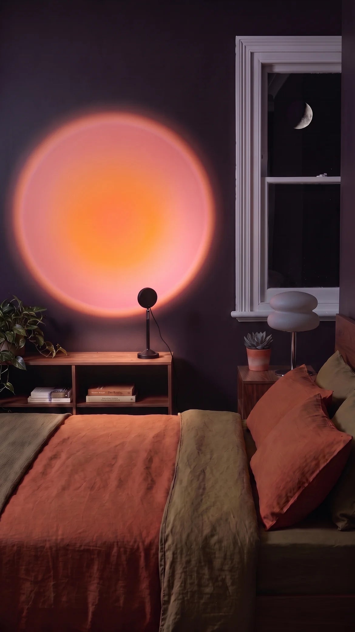 The sunset lamp throwing a round orange and pink glow on the wall